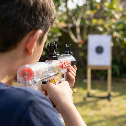 Child holding a toy gun with a target in the background
