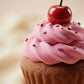Chocolate cupcake with pink frosting and a cherry on top against a blurred background