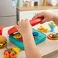 Child playing with colorful toy kitchen set on a kitchen counter.