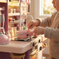 Child playing with a toy kitchen set in a bright room