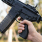 Hand holding a black rifle with a blurred natural background